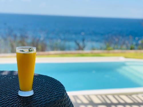 珀尼达岛Villa Argia Nusa Penida的坐在游泳池畔的桌子上喝杯啤酒
