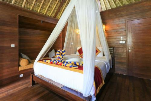 蓝梦岛Lembongan Mantra Huts - CHSE Certified的一间卧室配有一张带蚊帐的床
