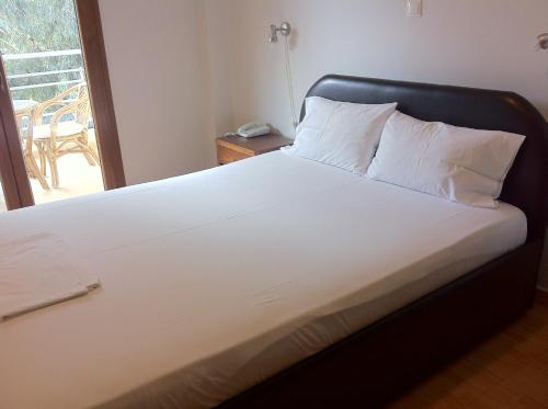 卢特拉艾季普苏玛歌诺拉公寓式酒店的一张白色的床,在房间里设有黑色床头板