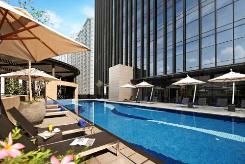 新加坡Carlton City Hotel Singapore的一个带遮阳伞和椅子的游泳池以及一座建筑