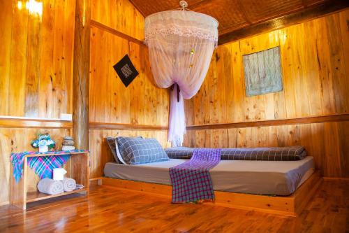 萨帕Sapa Orange Homestay的木制客房内的一间卧室,配有一张床