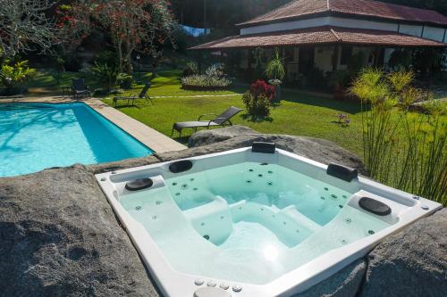 BarrinhaHotel Fazenda Bela Riba的游泳池旁的岩石上设有浴缸