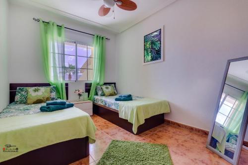 洛斯尼托斯Apartamento Havana的配有绿窗帘和镜子的客房内的两张床