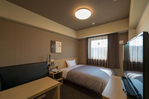 宇都宫Hotel Route-inn Utsunomiya Yuinomori -Lightline Yuinomori Nishi-的酒店客房设有床和窗户。