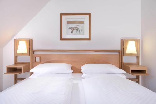 纽伦堡纽伦堡阿格尼斯舍弗酒店的两张床位于带两盏挂在墙上的灯的房间