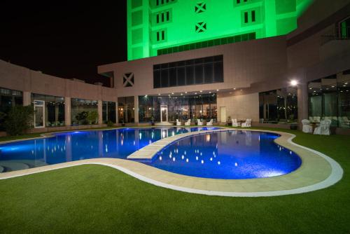 布凯里耶Ramada Hotel & Suites by Wyndham Al Qassim的一座游泳池,在晚上在建筑物前