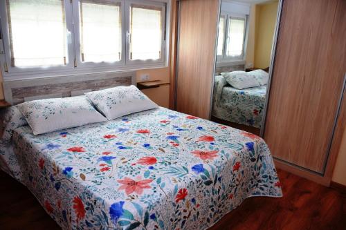 塞埃O Mencer do Camiño的一间卧室配有一张带花卉被子和镜子的床