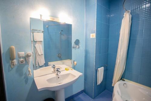 塔什干荣耀酒店的蓝色的浴室设有水槽和淋浴