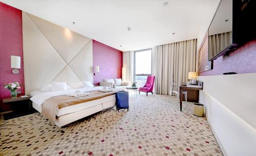 热舒夫热兹佐酒店的酒店客房设有一张大床和粉红色的墙壁。