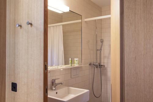 SalensteinHotel Arenenberg的浴室配有盥洗盆和带镜子的淋浴