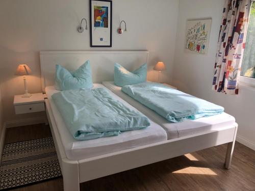 威克奥夫弗尔Bungalow 3的一张白色的床,上面有蓝色枕头