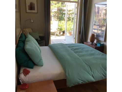海牙Bed & Breakfast Leonie的卧室内的一张带绿色床单和枕头的床
