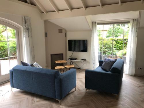 埃尔默洛Villa Felix with sauna in Ermelo的客厅配有2张蓝色沙发和电视
