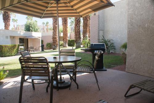 棕榈泉Desert Isle Resort, a VRI resort的桌椅、雨伞和烧烤架