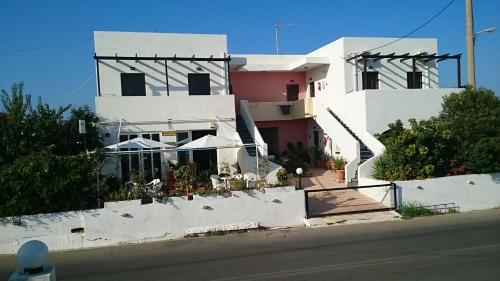 科林瓦里奥Iliaktida Apartments的前面有桌子和遮阳伞的白色建筑
