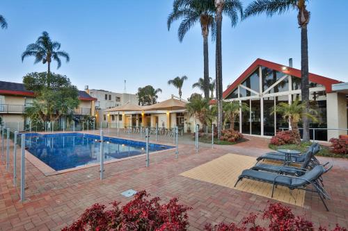 米尔迪拉米尔迪拉内地人度假村的一个带椅子和棕榈树的游泳池的度假酒店