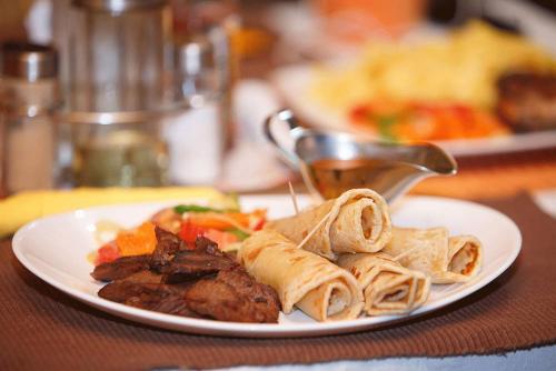 坎帕拉Shangri-La Fortune Hotel的桌上一盘带肉和面食的食物