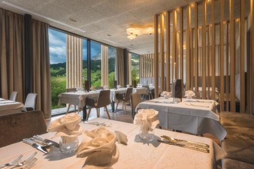 巴迪亚莱赫大桑彭酒店的餐厅设有白色的桌椅和大窗户。