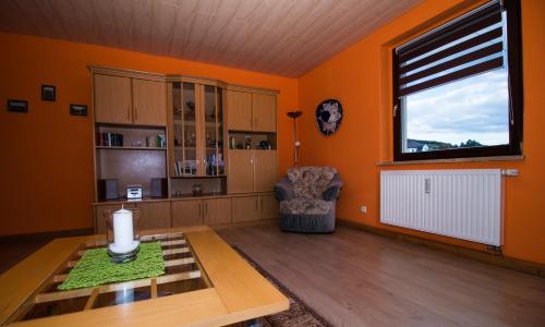 Bernsbacham Balkon des Erzgebirges的客厅设有橙色墙壁、桌子和窗户