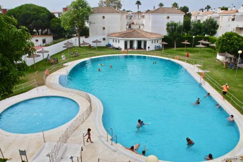 罗塔Apartamento Playa y Bosque的大型游泳池的顶部景色,里面的人