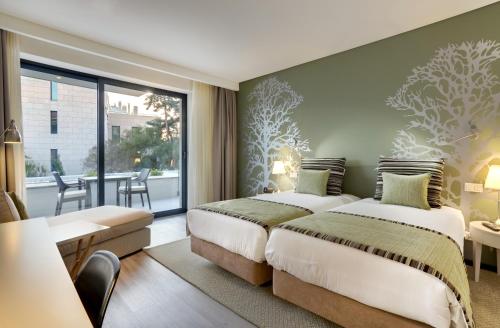 埃斯托利尔Hotel Inglaterra - Charme & Boutique的带阳台的酒店客房内的两张床