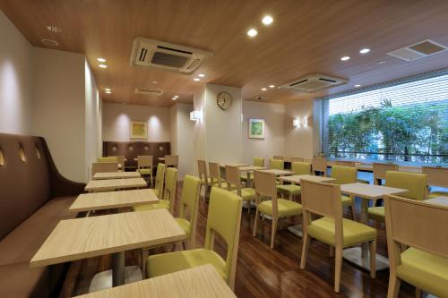 东京Keio Presso Inn Gotanda的餐厅设有木桌和黄色椅子