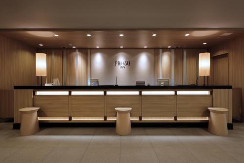 东京Keio Presso Inn Gotanda的大堂前设有带2把凳子的柜台