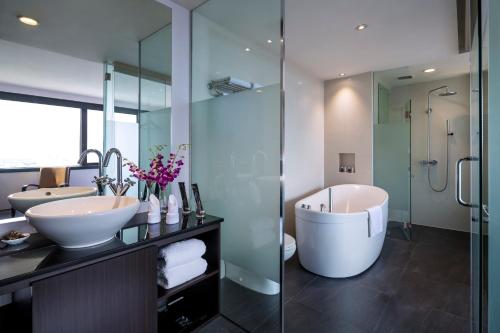 新加坡Furama City Centre的浴室配有2个盥洗盆、浴缸和淋浴。