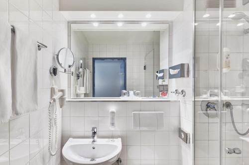 陶努斯山麓霍夫海姆法兰克福机场西H+酒店的白色的浴室设有水槽和淋浴。