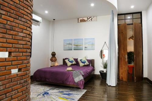 岘港Chaca House的一间卧室配有紫色的床和砖墙