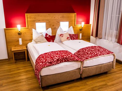 MöderbruggLandhotel Timmerer的红色墙壁的酒店客房内的两张床