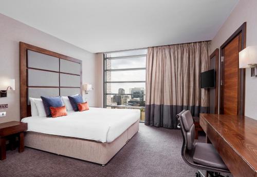 伦敦Leonardo Royal London Tower Bridge的配有一张床、一张书桌和一扇窗户的酒店客房