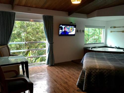 伊利亚贝拉Suites na Casa da Praia的卧室配有一张床,墙上配有电视。