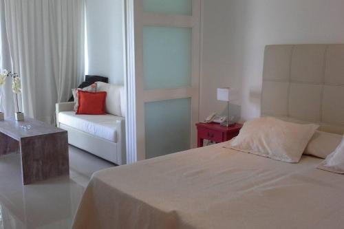 埃斯特角城Green Park Apartamento con Balcón vista Lago的一间卧室配有一张床、一张沙发和一把椅子