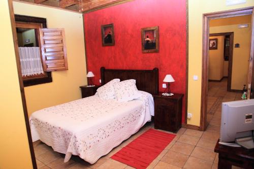 San Roque de Ríomiera旧学校旅馆的一间卧室设有一张床和红色的墙壁