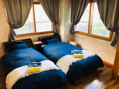 野沢Apartment at Toemu Nozawa的带窗户的客房内的2张蓝色床