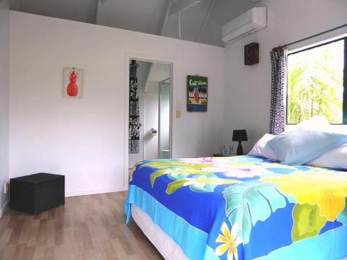 拉罗汤加Taakoka Muri Beach Villa的一间卧室配有一张色彩缤纷的床和一扇窗户