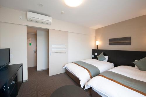 下关多美迎PREMIUM下关酒店的酒店客房设有两张床和电视。