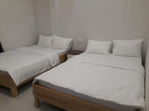 大叻Guest house Hai Cô Chú的配有2张床的带白色床单和枕头的客房