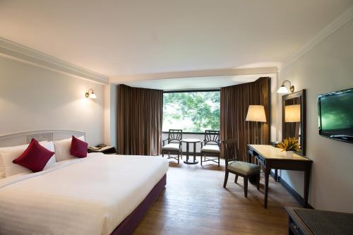 彭世洛The Imperial Hotel & Convention Centre Phitsanulok的酒店客房设有一张大床和一张书桌。