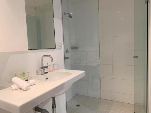 墨尔本墨尔本大都会酒店的白色的浴室设有水槽和淋浴。