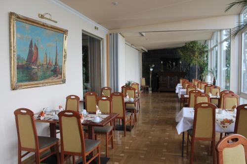 瓦尔内明德斯托尔特拉酒店的用餐室配有桌椅,墙上挂有绘画作品
