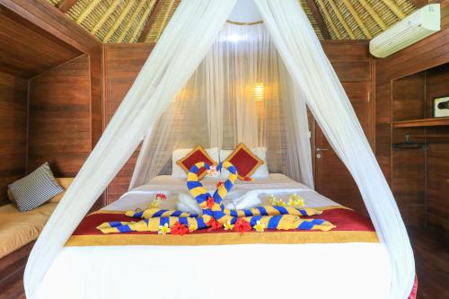 蓝梦岛Koji Garden Huts - CHSE Certified的一间卧室配有一张带蚊帐的床