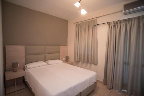 ChortátaT'Aloni的卧室配有白色的床和窗户。