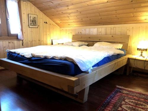 CrésuzCharmant Petit Chalet 3 étoiles en Gruyère的木制客房内的一间卧室配有一张大床
