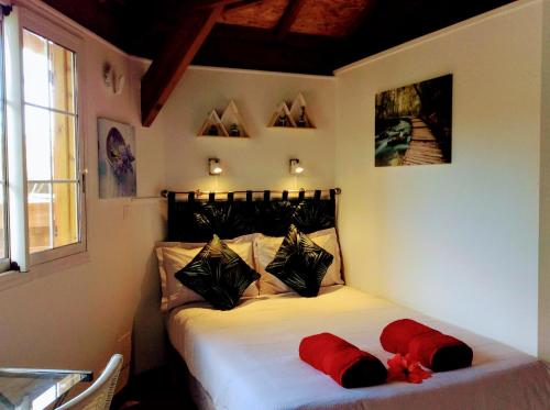 Saint-Gilles-les HautsChalet "BIENVENUE NOUT KAZ"的一间卧室配有一张带两个红色枕头的床