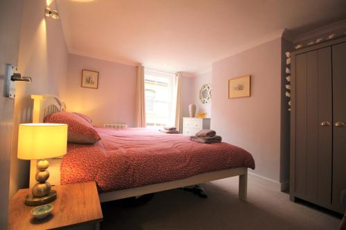 坎特伯雷1 Steam Packet Cottage的一间卧室配有一张带红色棉被的床和窗户。