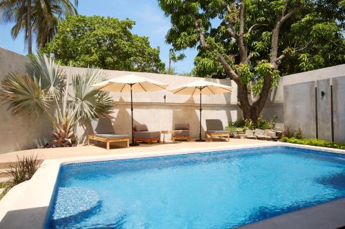 松索纳特Villavela Hotel Boutique的庭院内带椅子和遮阳伞的游泳池