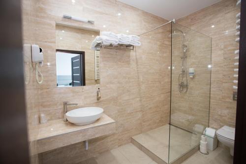 卢巴瓦新城Hotel Tiffany的一间带水槽和玻璃淋浴的浴室