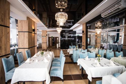 卢巴瓦新城Hotel Tiffany的用餐室配有白色的桌子和蓝色的椅子
